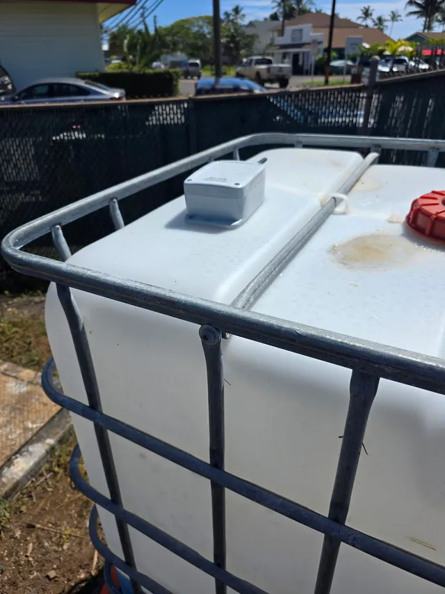 Close-up of an ultrasonic tank level sensor mounted on the lid of an IBC tote dosing tank
